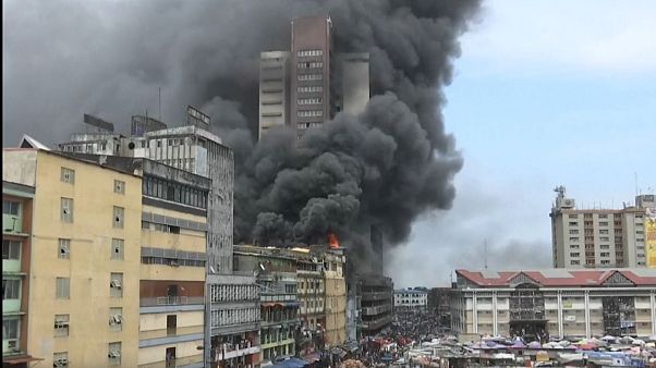 Image result for Goods were thrown out of windows to save stock while men on the roof of ... Market buildings are ablaze in Nigeria's commercial capital,