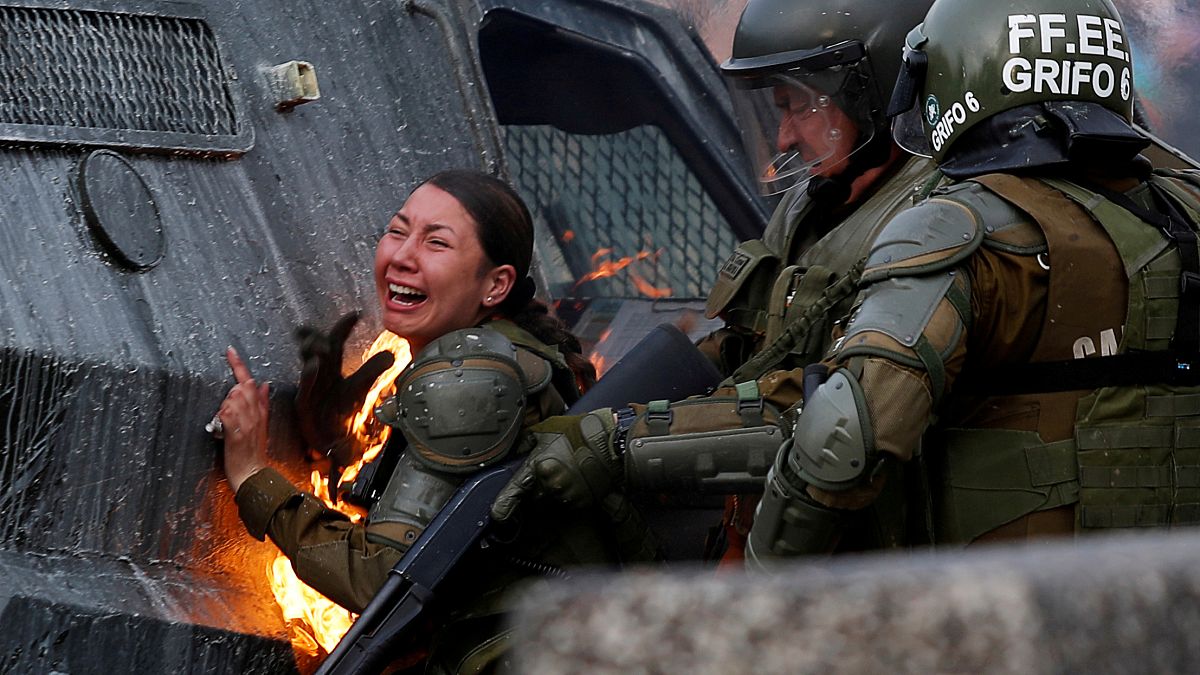 Una mujer policía en llamas durante los disturbios del lunes en Santiago