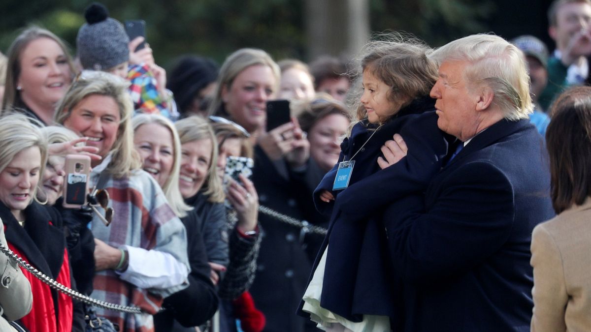 U.S. President Donald Trump poses for pictures with a child as he departs for travel to Georgia from the South Lawn of the White House in Washington, U.S.