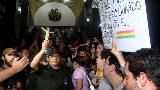 A police officer holds a crucifix as opponents to Bolivia's President Evo Morales cheer in Santa Cruz de la Sierra, Bolivia, November 8, 2019. 