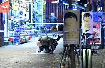 A police officer marks evidence at the crime scene where a 15-year-old was fatally hit and another severely wounded when attackers opened fire on a pizzeria