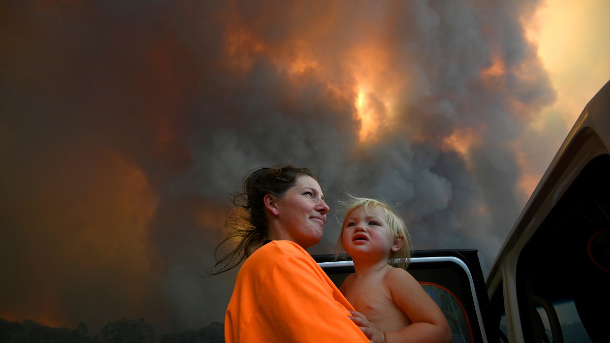 أم وطفلها ينظران إلى سحب دخان النيران الكثيف يتصاعد من الغابات المحترقة بالقرب من نانا غلين - 2019/11/12 -