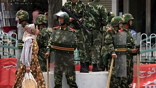 Doğu Türkistan'ın Urumçi kentinde, Çinli askerlerin önünden geçen Uygur kadın