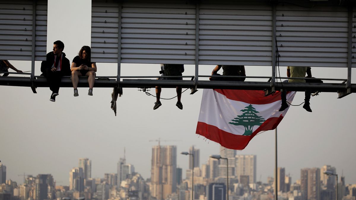 متظاهرون يجلسون على لافتة على طريق مظاهرة تسد الطريق السريع خلال الاحتجاجات المستمرة المناهضة للحكومة في الحازمية، لبنان 13 نوفمبر/ تشرين الثاني 2019
