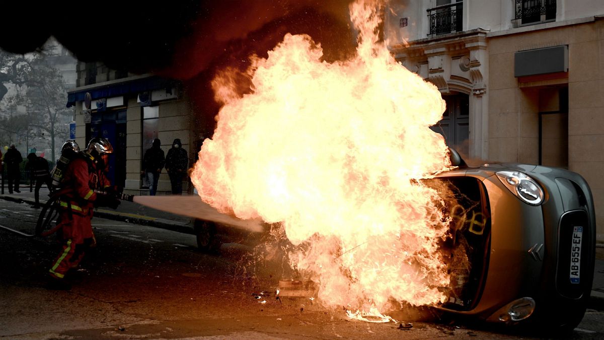 A firefighter tries to extinguish a burning car on place d'Italie in Paris on November 16, 2019