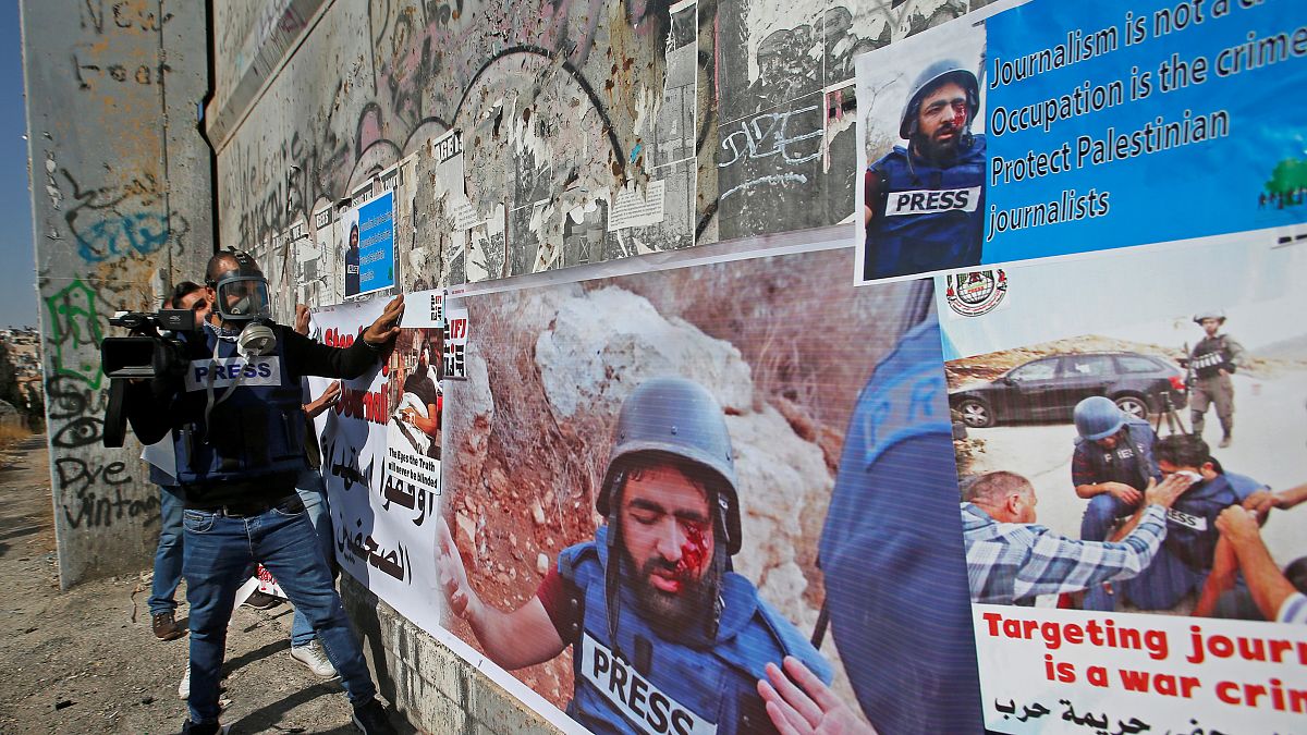  صحفيون فلسطينيون يضعون ملصقات تظهر زميلهم معاذ العمارنة الذي أصيب بعيار ناري في عينه تضامنا معه في بيت لحم في الضفة الغربية