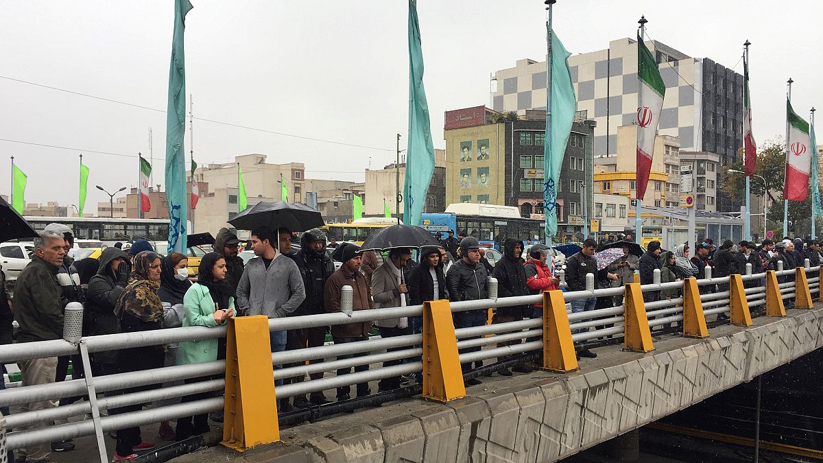 People stands in the street to show their protest against increased gas price in Tehran