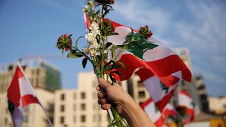 لبنانية ترفع علم لبنان وباقة من الزهور خلال "الاحتفال المدني" بعيد الاستقلال السادس والسبعين في بيروت