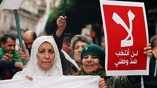 إمرأة جزائرية ترفع ملصقا في الجزائر العاصمة- أرشيف رويترز