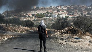 فلسطيني يقف أمام مستوطنة كدوميم بالقرب من الضفة الغربية- أرشيف رويترز