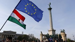 People wave Hungarian and European Union flags as they protest in Heroes’ square  in Budapest, Hungary
