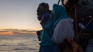 Some of the people onboard the Aita Mari look at the island of Sicily