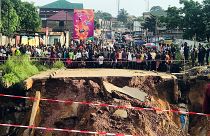 Des habitants de Kinshasa, devant une route coupée en deux.