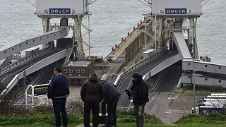 Men look across the English Channel towards France through a telescope at the Port of Dover in Britain
