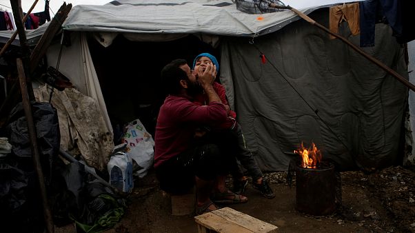 لاجئ سوري يعانق ابنه بالقرب من خيمة للجوء في اليونان لاجئ سوري يعانق ابنه بالقرب من خيمة للجوء في اليونان
