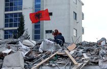 Rescue workers marked Albania's Flag Day by flying a flag above the rubble of a quake-collapsed building in Durres. 