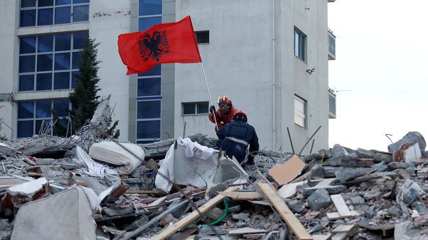 Rescue workers marked Albania's Flag Day by flying a flag above the rubble of a quake-collapsed building in Durres. Rescue workers marked Albania's Flag Day by flying a flag above the rubble of a quake-collapsed building in Durres.