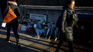 Commuters walk past flowers and signs left at the scene of a fatal attack on London Bridge in London, Britain December 2, 2019. 