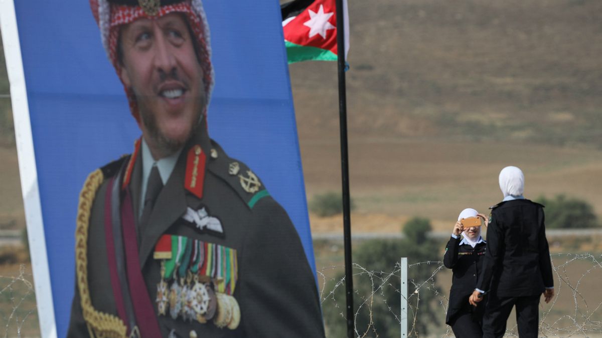 شرطيات أردنيات يلتقطن صوراً بجوار ملصق للعاهل الأردني الملك  عبد الله الثاني