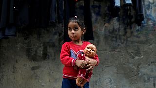 Palestinian girl of Radhi family holds a doll outside her family home in Al-Shati refugee camp in Gaza City