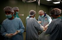 أطباء يقومون بعملية جراحية لفلسطيني مصاب في غرفة عمليات في مستشفى بمدينة غزة