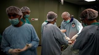 أطباء يقومون بعملية جراحية لفلسطيني مصاب في غرفة عمليات في مستشفى بمدينة غزة