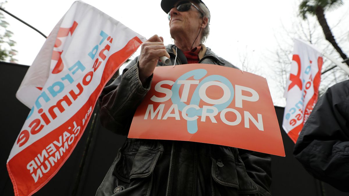 متظاهر في فرنسا يحمل لافتة كتب عليها "أوقفوا ماكرون" 