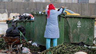 امرأة تجمع قارورات البلاستيك من صندوق للقمامة في تونس