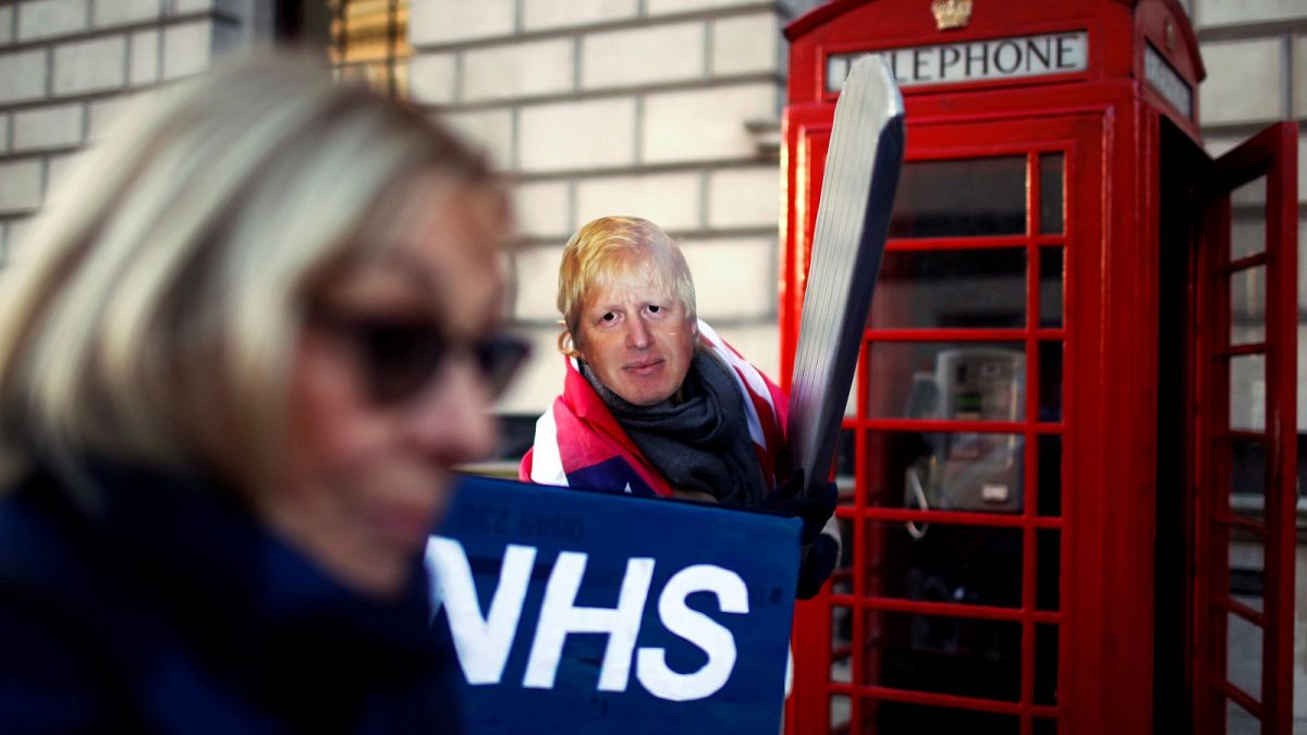 A healthcare professional dressed as Britain's Prime Minister Johnson attends a demonstration demanding NHS public service must remain protected from commercial exploitation