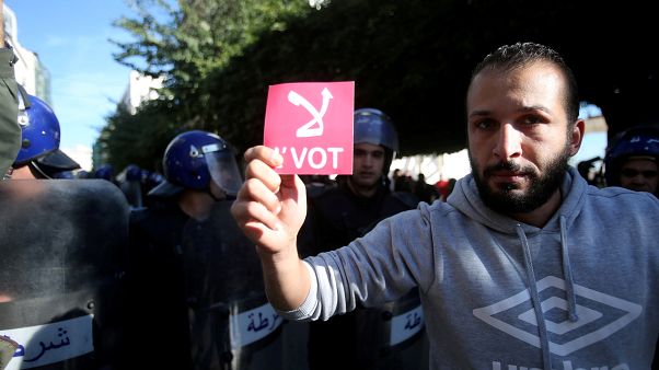 A demonstrator holds a card during a protest calling to reject the upcoming presidential election in Algiers, Algeria December 11, 2019. A demonstrator holds a card during a protest calling to reject the upcoming presidential election in Algiers, Algeria December 11, 2019.