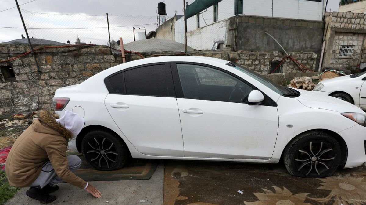 رجل فلسطيني يتفقد إطارات سيارته بعد حملة تخريب في شعفاط القدس الشرقية- أرشيف رويترز 