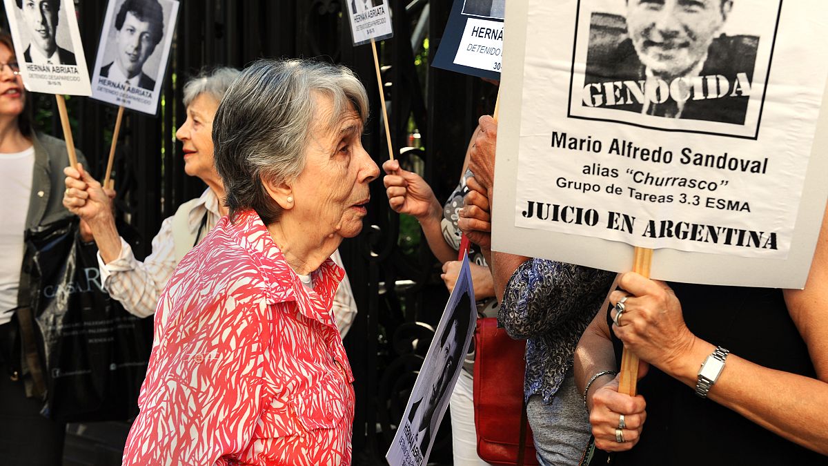 Beatriz Cantarini de Abriata, mother of Hernan Abriata stands next to a portrait of former Argentine police officer Mario Sandoval