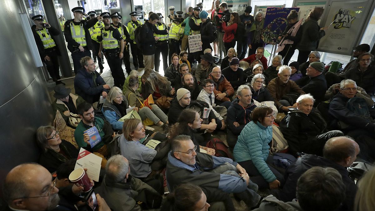 Police Officers stand guard as Extinction Rebellion demonstrators peacefully block an entrance to City Airport in London, Thursday, Oct. 10, 2019.