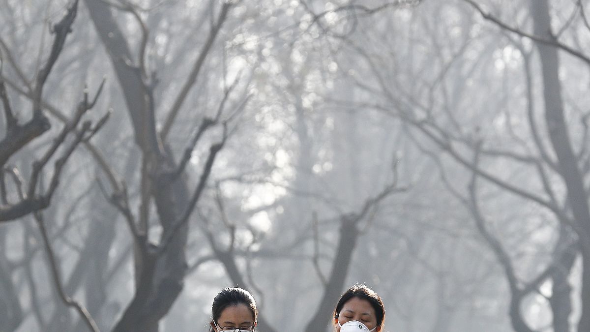 Deux femmes se protègent avec un masque, décembre 2016, à Pékin, Chine