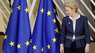 European Commission President Ursula von der Leyen looks at the EU flag prior to a group photo during an EU summit in Brussels, Thursday, Dec. 12, 2019.