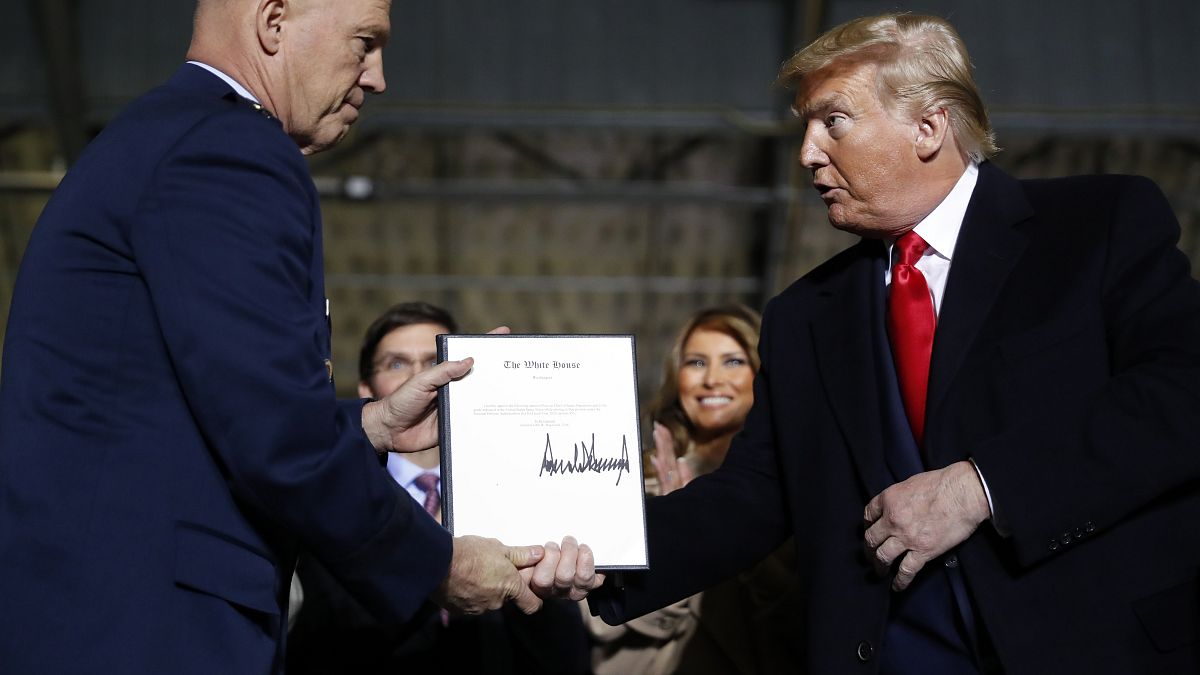 President Donald Trump shakes hands with General Jay Raymond after signing letter appointing him to the U.S. Space Command