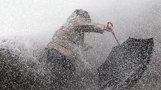 A woman tries to keep her balance as waves hit the seawall in Biarritz, southwestern France, Sunday, Dec.22, 2019