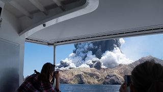In this Dec. 9, 2019, file photo provided by Michael Schade, tourists on a boat look at the eruption of the volcano on White Island, New Zealand.