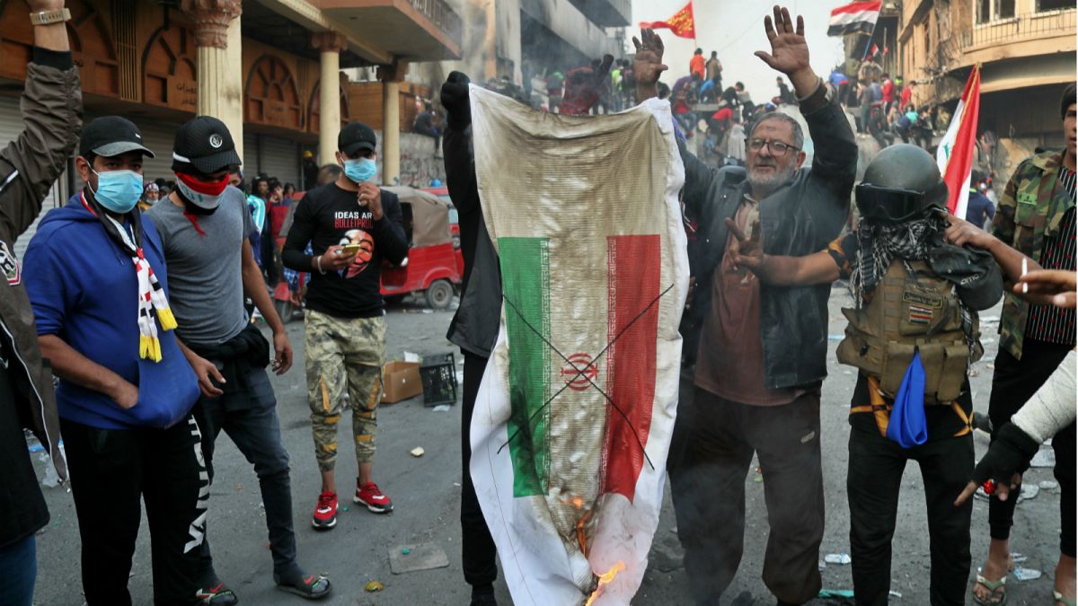 متظاهر عراقي يحرق العلم الإيراني في بغداد 