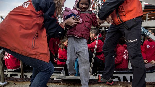 Einem Jungen wird von Helfern im spanischen Algeciras an Land geholfen. Einem Jungen wird von Helfern im spanischen Algeciras an Land geholfen.