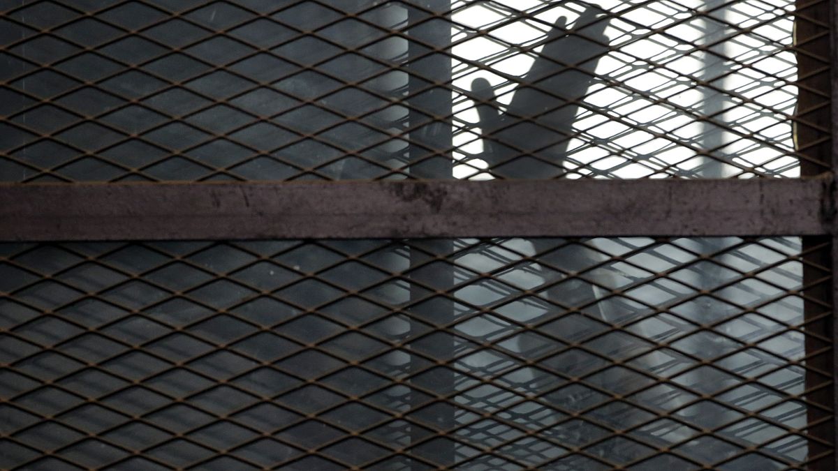 In this Aug. 22, 2015 file photo, a Muslim Brotherhood member waves his hand from a defendants cage in a courtroom in Torah prison, southern Cairo, Egypt.