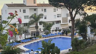 In this photo taken on Tuesday Dec. 24, 2019, Civil guard divers, right, work at the side of a swimming poo at the Club La Costa World holiday resort near Malaga, Spain.