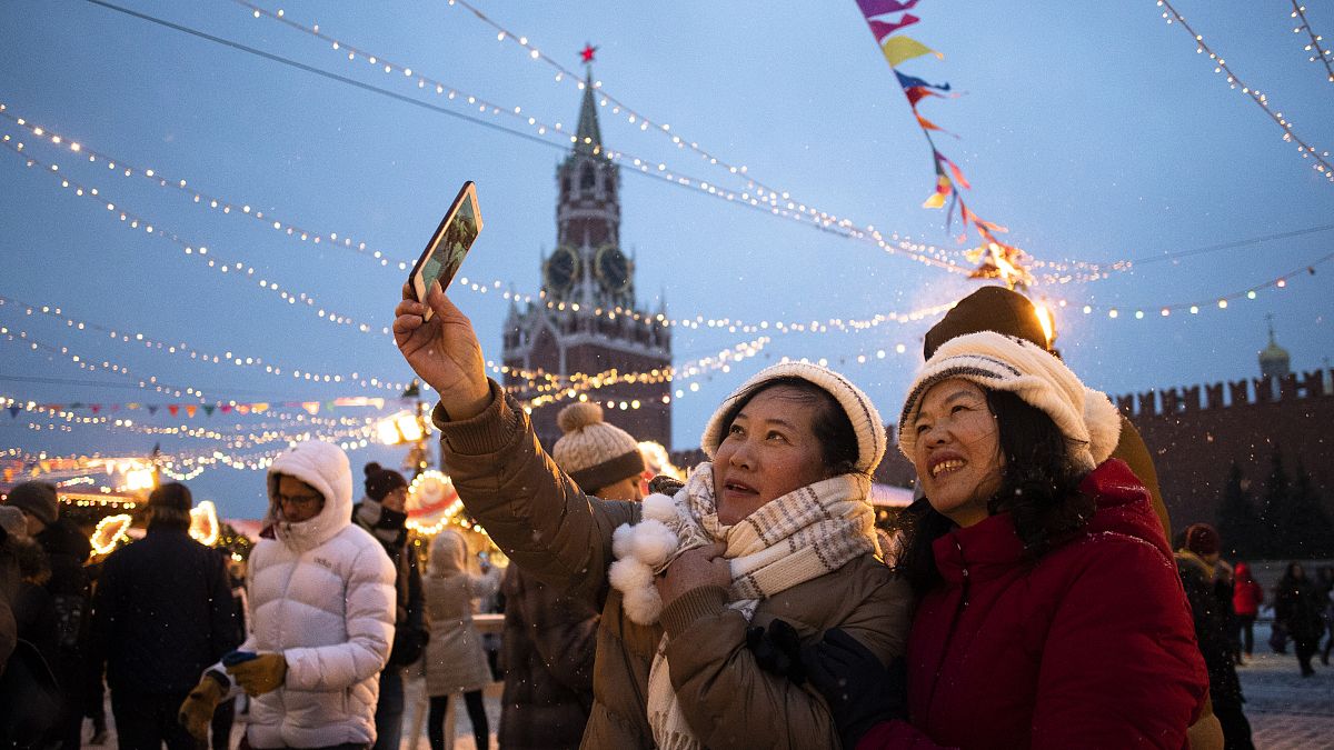 Tourists take a selfie in Red Square decorated for New Year celebrations, with the the Kremlin's Spasskaya Tower in the background, in Moscow, Russia.