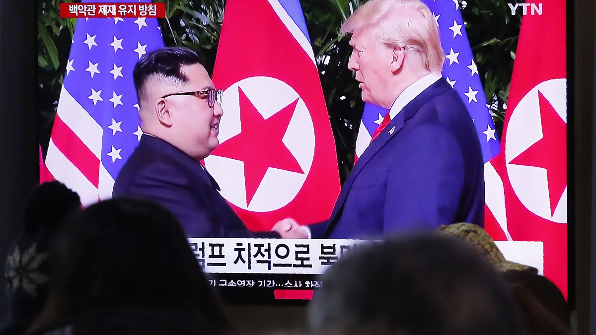Espetadores assistem a imagens de arquivo de um encontro entre os líderes da Coreia do Norte e dos EUA