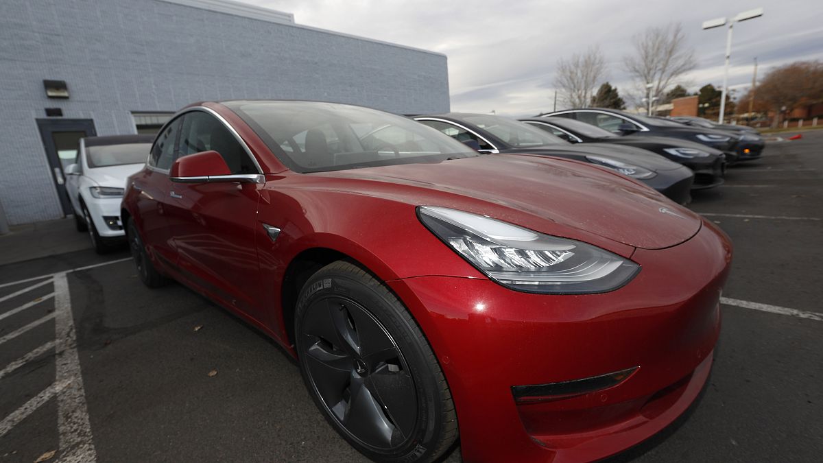 In this Sunday, Nov. 10, 2019, photograph, a long row of unsold 2020 Model 3 sedans sits at a Tesla dealership in Littleton, Colo. (AP Photo/David Zalubowski)