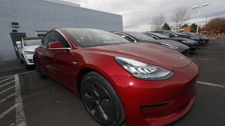 In this Sunday, Nov. 10, 2019, photograph, a long row of unsold 2020 Model 3 sedans sits at a Tesla dealership in Littleton, Colo. (AP Photo/David Zalubowski)