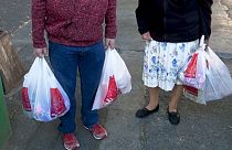 Dos mexicanos cargan bolsas de plástico tras salir de la compra