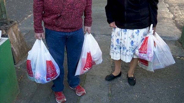 Dos mexicanos cargan bolsas de plástico tras salir de la compra Dos mexicanos cargan bolsas de plástico tras salir de la compra