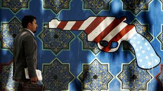 An Iranian man walks pass an anti-U.S. graffiti painted on the wall of the former U.S. Embassy in Tehran