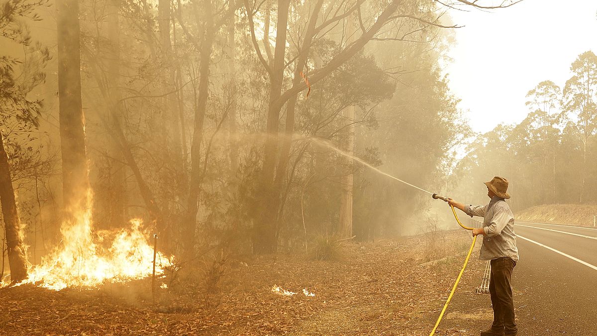 رجل يستخدم خرطوم مياه لمحاربة حريق بالقرب من مورويا في أستراليا، 4 يناير 2020